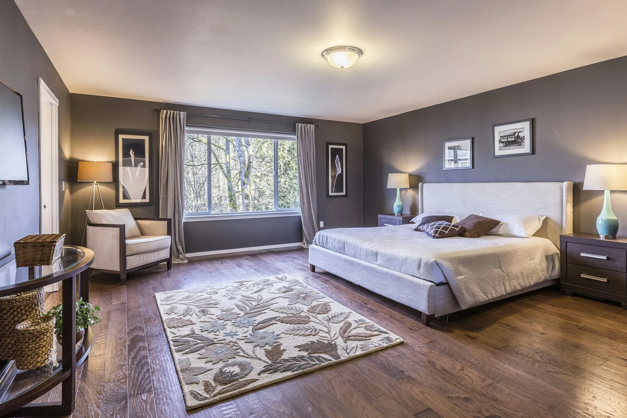 Spacious bedroom with wood floors, a large window and a sitting area