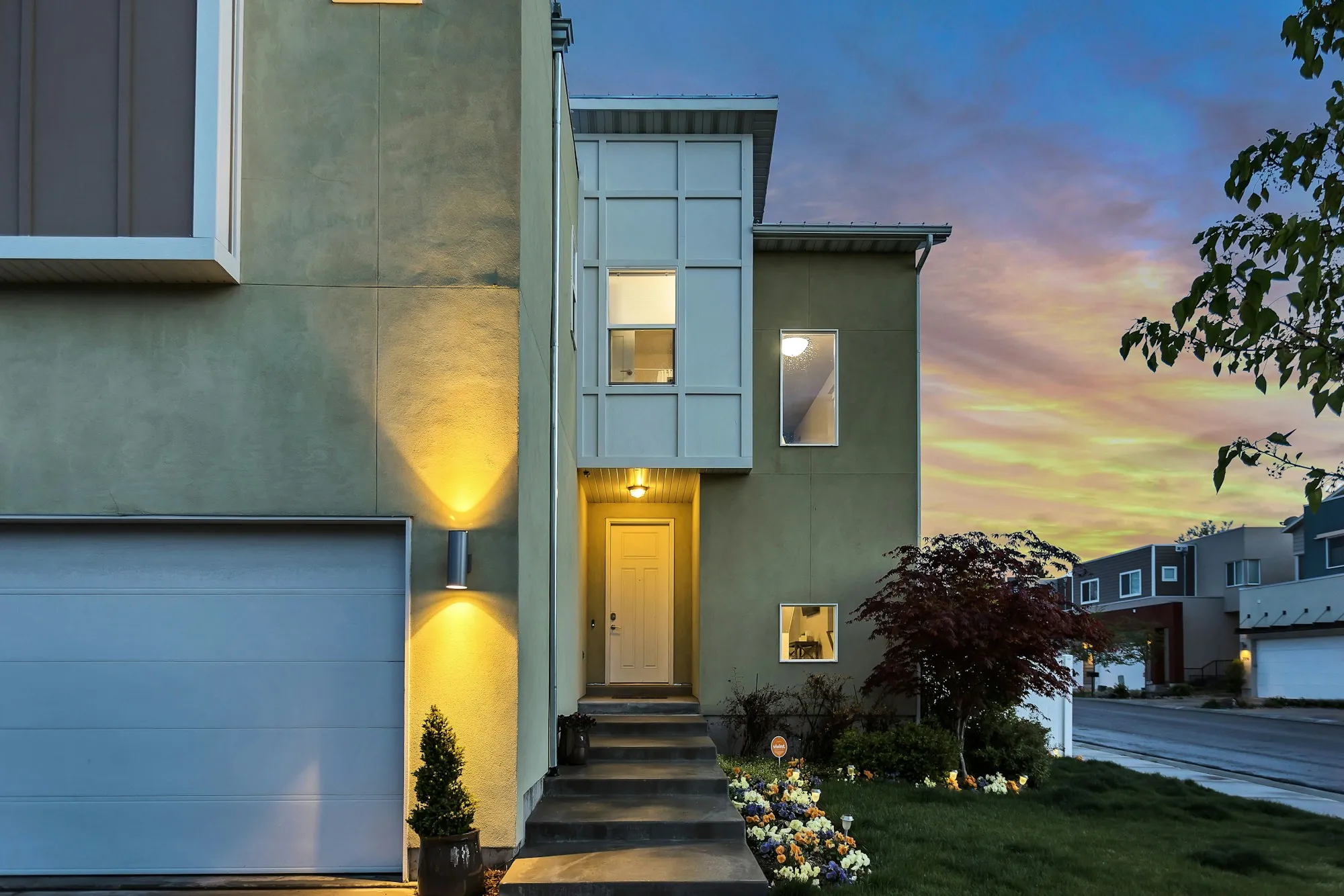 Modern house with a garage and wall lights at sunset